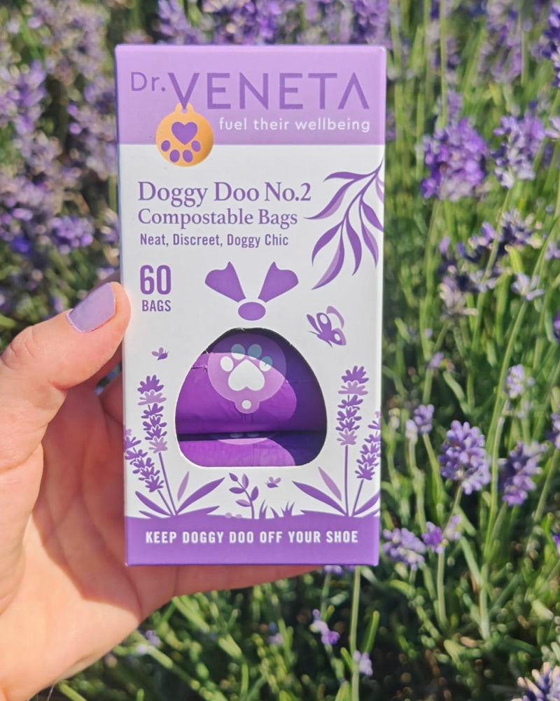 A hand with lavender-painted nails holds a box of Dr. Veneta Doggy Doo No.